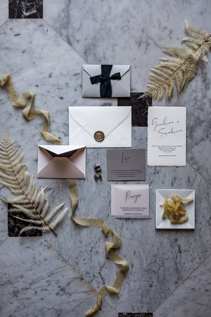 Black, white, and gold wedding invitation suite against marble tile flooring at Villa Astor in Sorrento Italy