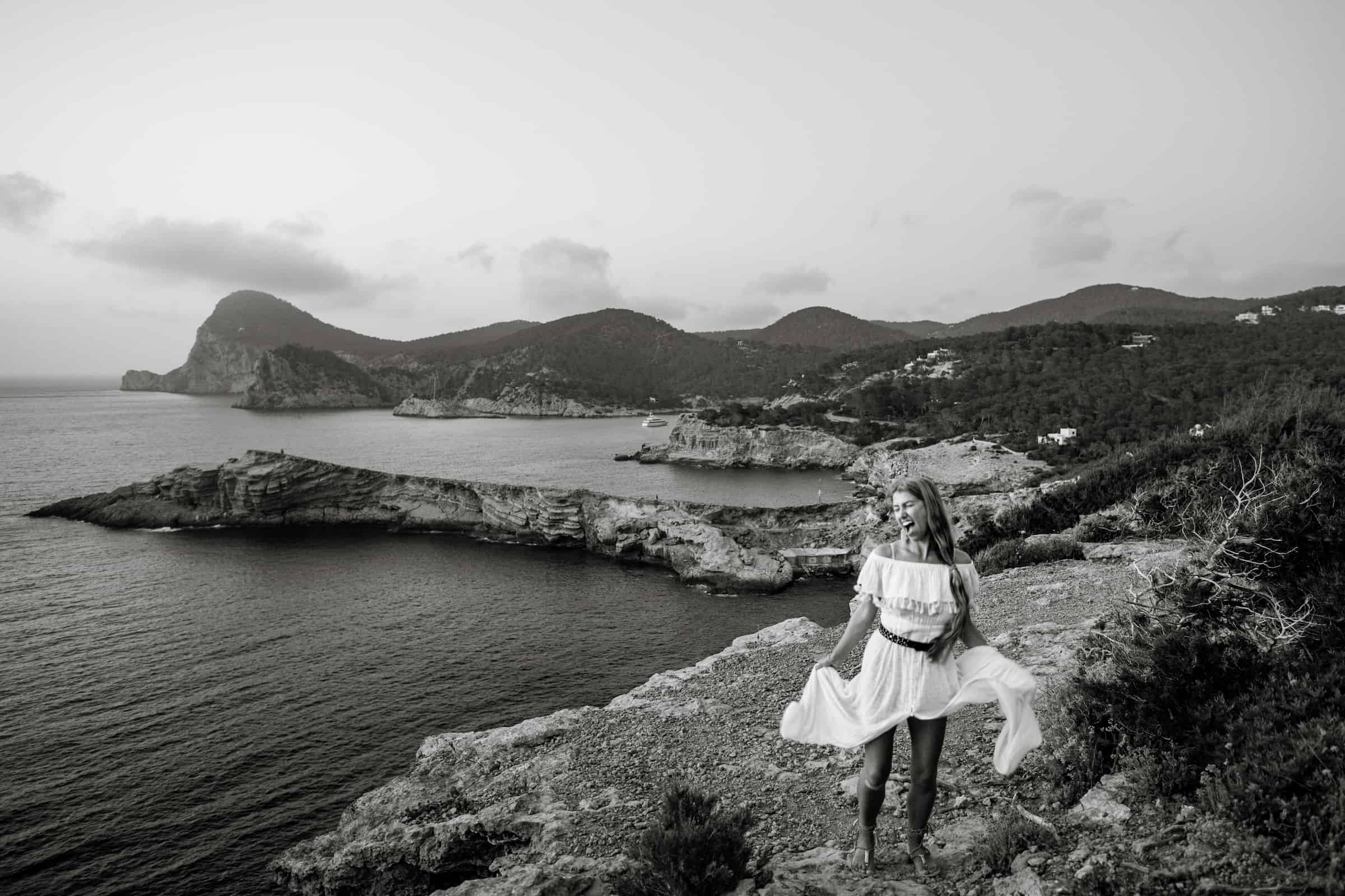 Lilly Red, a destination wedding photographer, explores a mountain next to the ocean after photographing a wedding