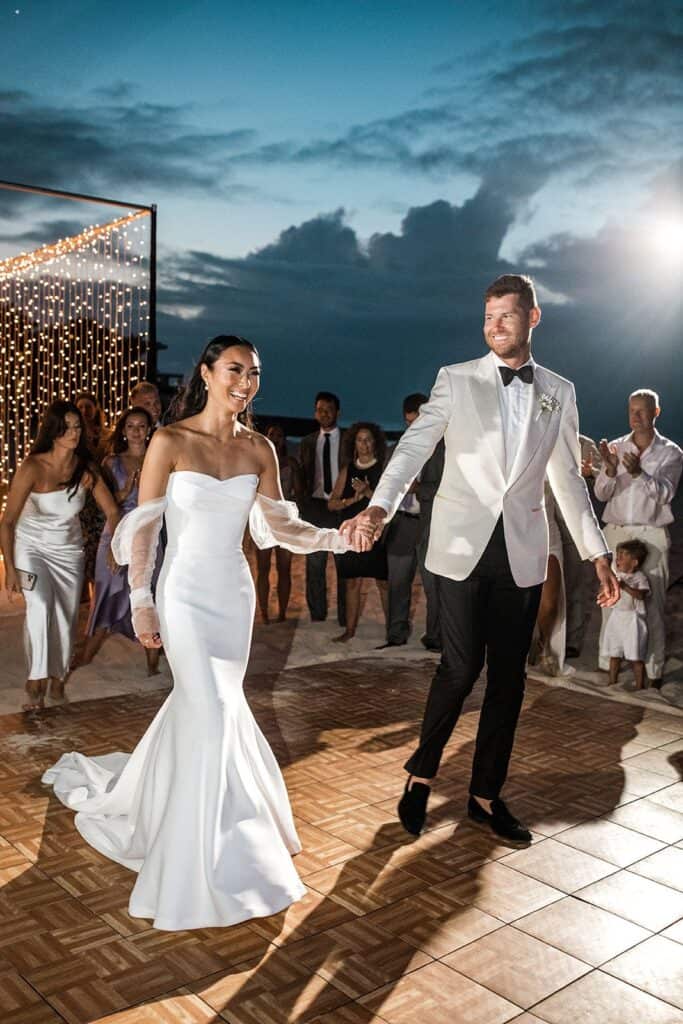Bride and groom walk onto wedding reception dance floor at a beach wedding at night