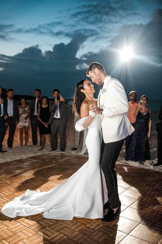 Bride and groom share first dance for outdoor beach wedding reception, captured by photographer with appropriate wedding photography equipment