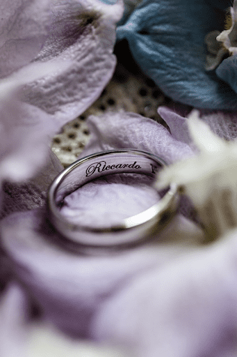 Wedding rings close up with flowers adding texture to background
