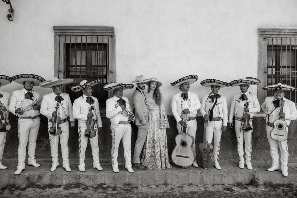 A bride and groom stand with a mariachi band in San Miguel de Allende after their wedding