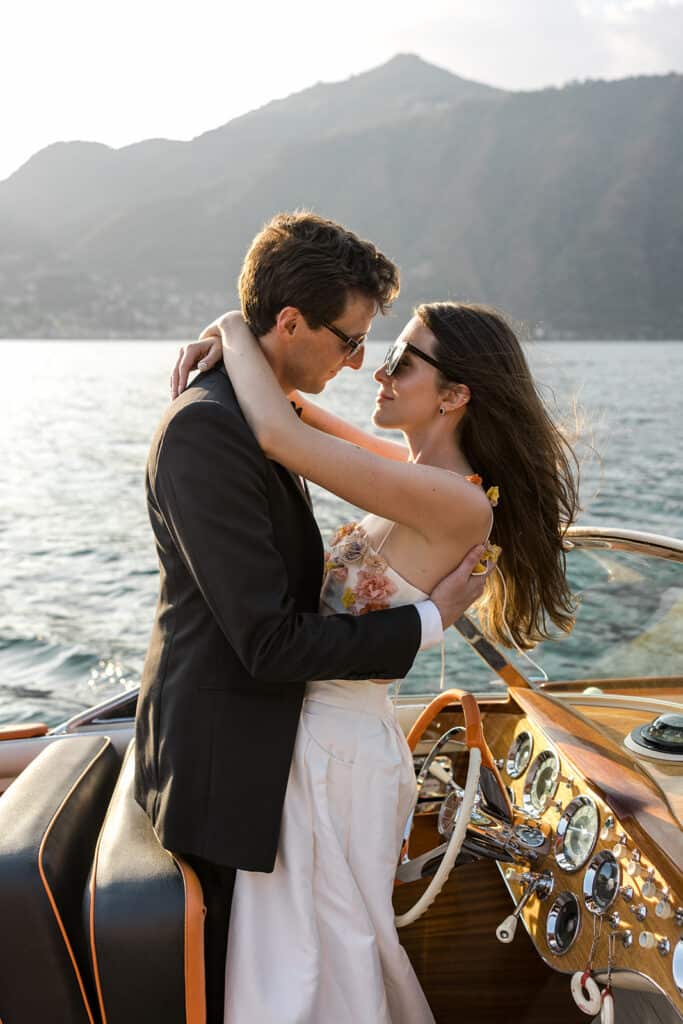 Bride and groom, upscale wedding clients, embrace on a boat on Lake Como