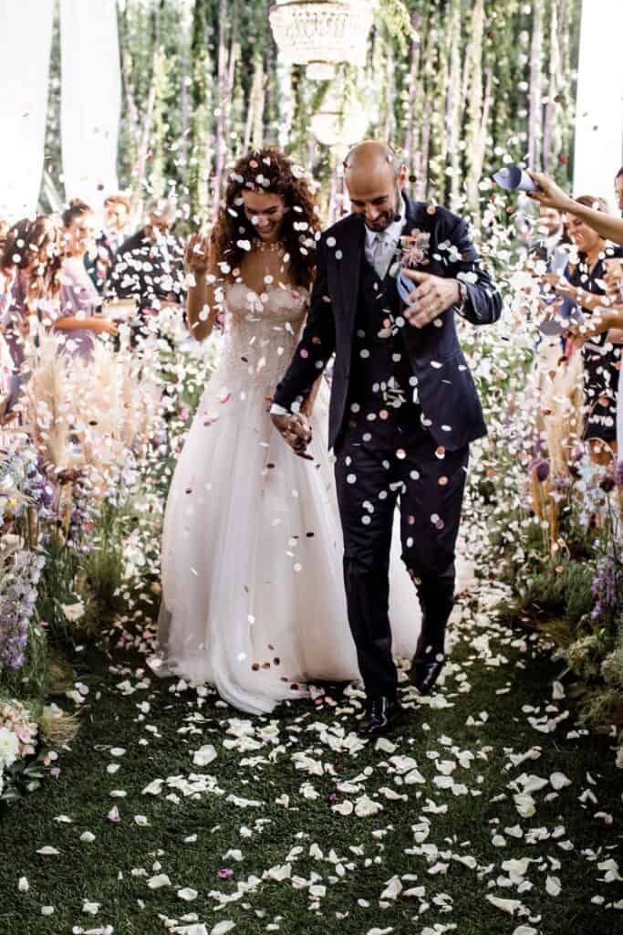 Bride and groom walk down aisle with confetti